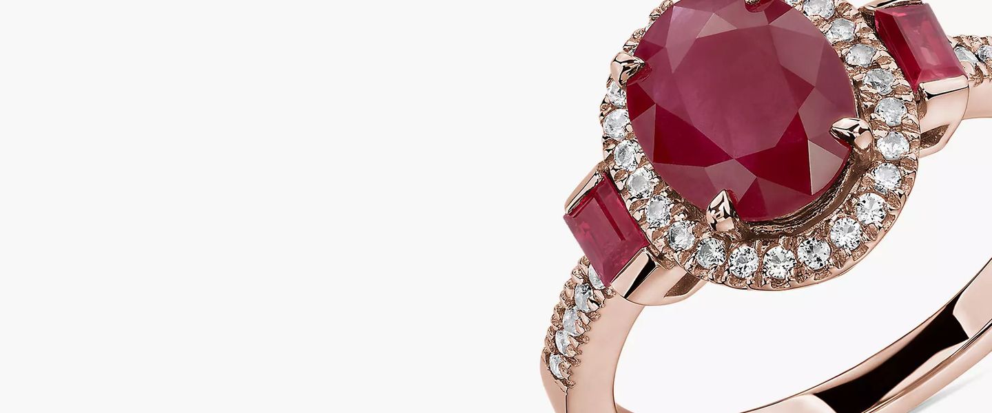 An oval cut ruby gemstone accented with baguettes featured in a rose gold ring